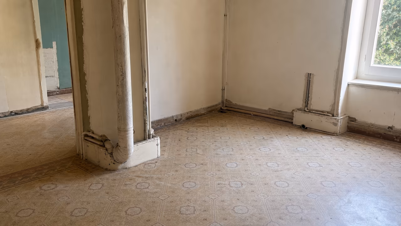 Dalles de sol vinyle-amiante et conduits anciens dans une maison en cours de rénovation