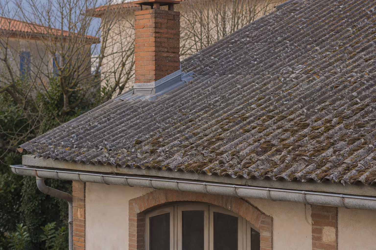 Toiture en plaques de fibrociment ondulé partiellement dégradée par la mousse sur un pavillon en Haute-Garonne